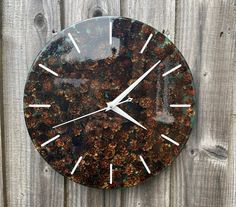 a clock that is on the side of a wooden fence with flowers painted on it