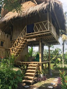 a wooden house with stairs leading up to the roof and steps down to the ground