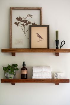 two wooden shelves with towels and other items on them in a white walled bathroom area