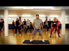 a group of people in a dance class with one man standing on a mat and the other holding a microphone