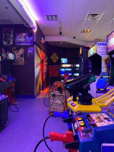 a room filled with video game machines and arcade gaming equipment on the walls, in front of purple lighting