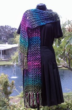 a woman's black dress with a multicolored crochet shawl draped over it