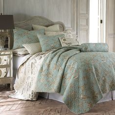 a bed with blue and white bedspreads in a room next to a lamp