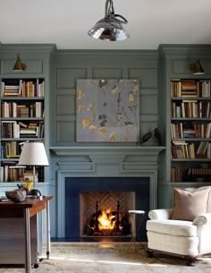 a living room filled with furniture and a fire place in front of a bookshelf