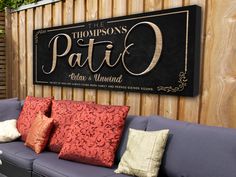 a blue couch sitting in front of a wooden fence with pillows on top of it