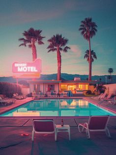 a motel with a swimming pool and lounge chairs in front of it at night time