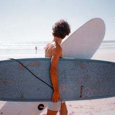 a man carrying a surfboard on the beach