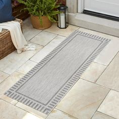 a door mat sitting on top of a tiled floor next to a potted plant