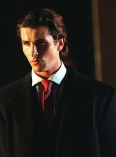 a man in a black suit and red tie