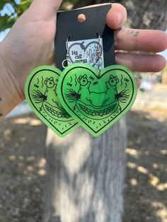 two green heart shaped stickers held in front of a tree