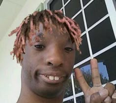 a man with dreadlocks making the peace sign