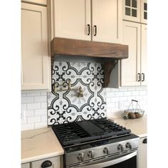 a stove top oven sitting inside of a kitchen next to white cabinets and counter tops