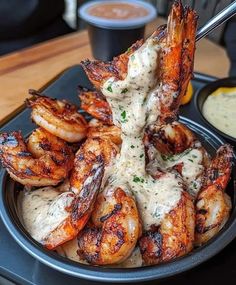 some shrimp is being served in a bowl on a tray with sauce and dipping sauce