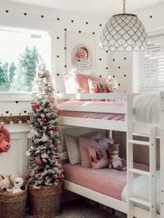 a white bunk bed sitting under a window next to a christmas tree in a room