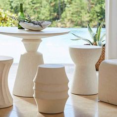 three white vases sitting next to each other on top of a table near a pool