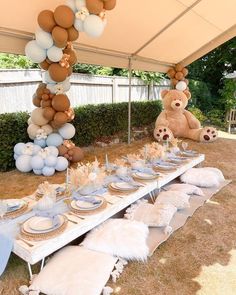 a table set up for a baby shower with balloons and teddy bears hanging from the ceiling