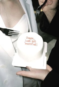 a woman holding a white cake with words on it and a fork in her hand