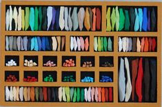 an assortment of different colored ties displayed in a wooden display case on a table top