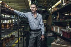 an older man standing in front of shelves with pots and pans on the shelves