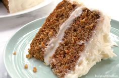 a slice of carrot cake with white frosting on a plate next to another piece of cake