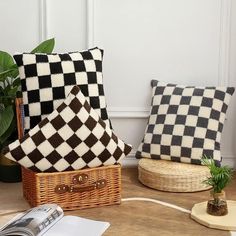 two black and white checkered pillows sitting on top of a table next to a plant