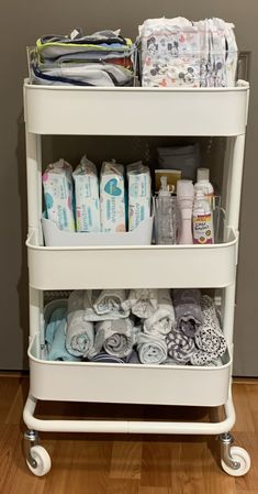 a white cart filled with lots of diapers and baby products on top of a hard wood floor