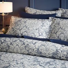 a bed with blue and white comforters in a bedroom next to a night stand