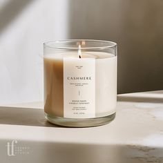 a candle sitting on top of a table next to a window sill with the words cashmere printed on it