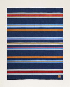 a blue, orange and red striped rug on a white background with a brown border