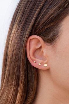 a close up of a woman's ear with two small gold dots on it