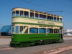 a green and white double decker bus driving down the street