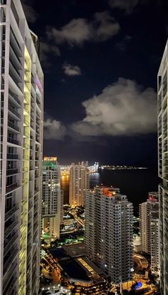 the city skyline is lit up at night with clouds in the sky and lights on buildings