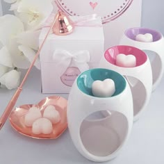 three white and pink vases sitting next to each other on a table with flowers in the background