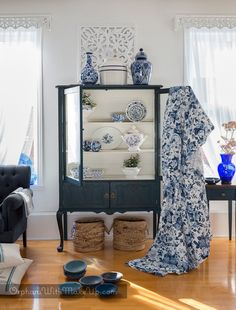 a china cabinet with blue and white dishes on it's glass doors in a living room