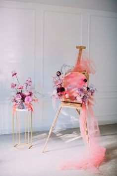 a chair with flowers on it next to a small vase filled with pink and purple flowers