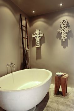 a white bath tub sitting in a bathroom next to a wooden cross on the wall