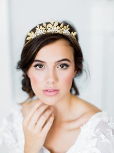 a woman wearing a tiara and holding her hand near her face