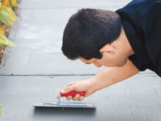 a man is using a tiler on the sidewalk