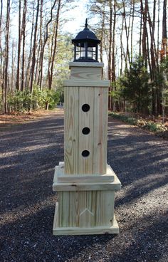 a wooden tower with a light on top sitting in the middle of a gravel road