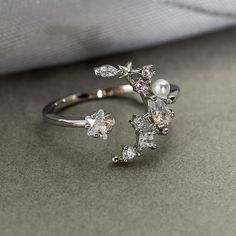 a close up view of a ring with pearls and diamonds on the side, sitting on a table