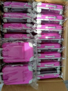 several pink and white suitcases in a cardboard box with plastic wrap around them on top of each other