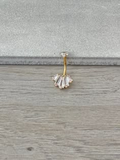 a pair of gold earrings sitting on top of a wooden floor next to a wall