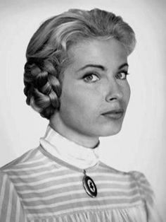 a black and white photo of a woman with braids in her hair wearing a striped shirt