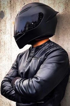 a man wearing a motorcycle helmet leaning against a wall