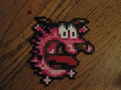 a piece of art made out of perler beads on a wooden table with a computer mouse