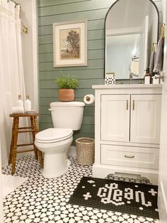 a white toilet sitting in a bathroom next to a wooden stool and sink with a mirror above it