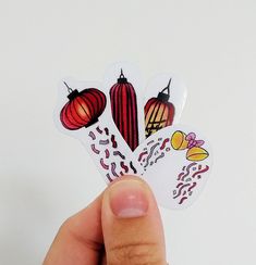 a hand holding up some stickers with different designs on them and an image of lanterns