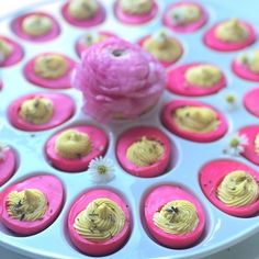 cupcakes with yellow frosting and pink icing on a white cake plate