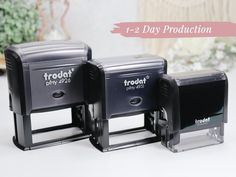 two black mailboxes sitting next to each other on a white table with text that reads 1 - day production