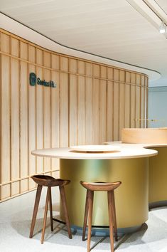 an office counter with two stools in front of it and a sign on the wall